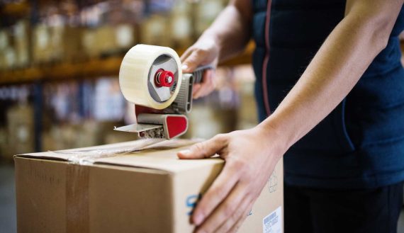 male-warehouse-worker-sealing-cardboard-boxes-PSKUTTE